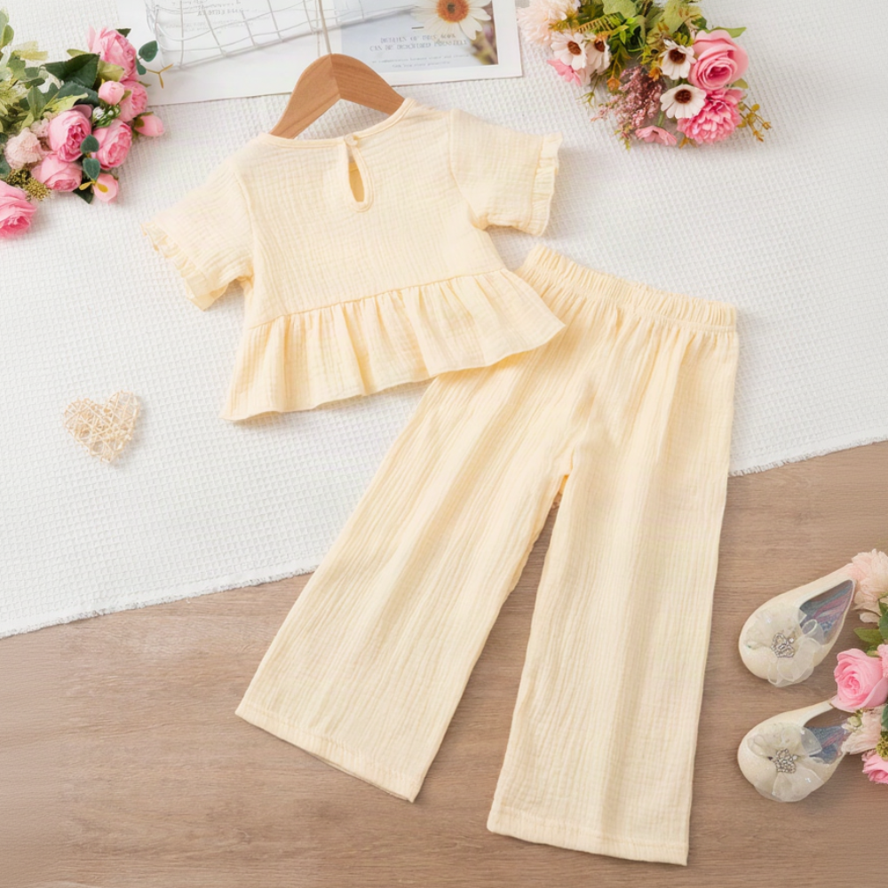 Beige ruffle top shown from the back beside matching long pants