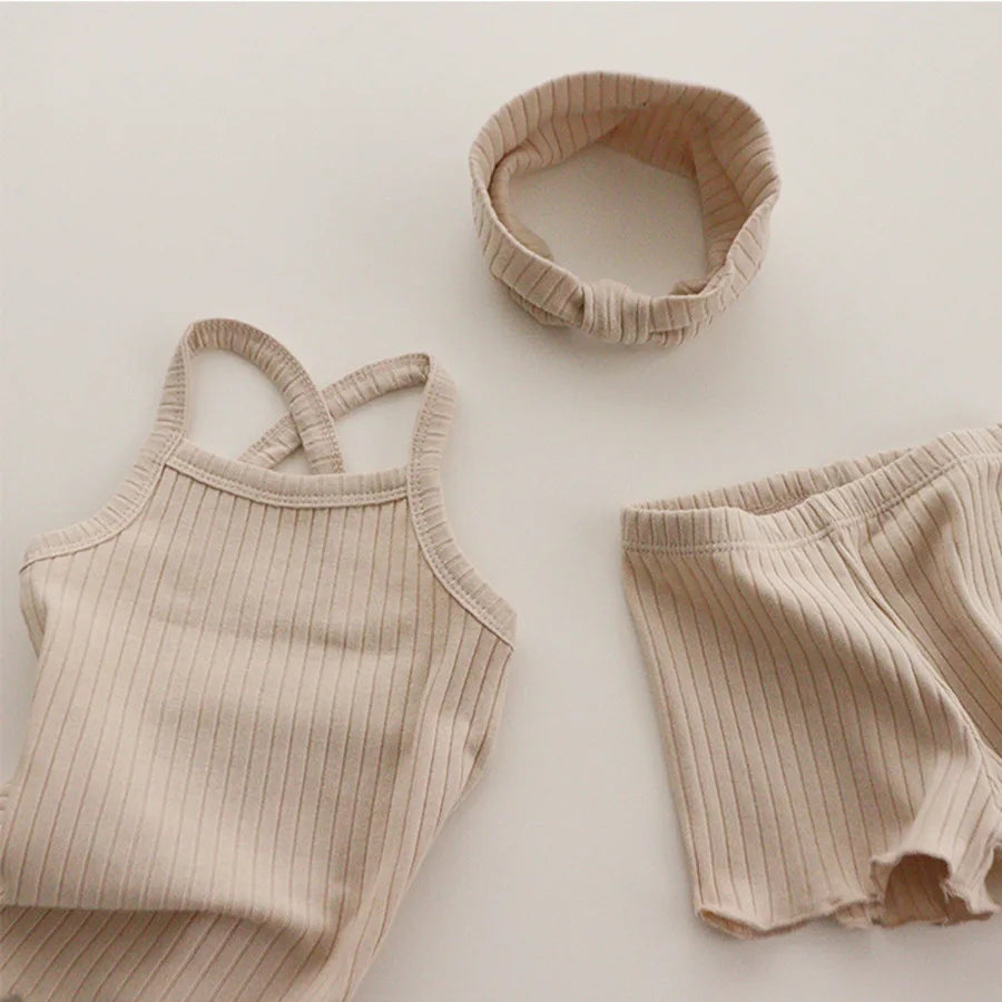 Beige ribbed pajama tank and shorts arranged beside a matching fabric headband