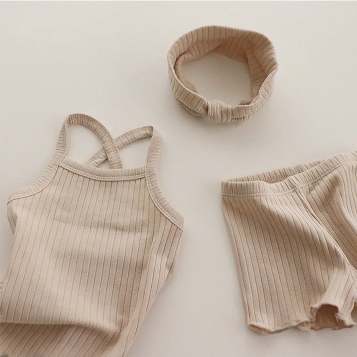 Beige ribbed pajama tank and shorts arranged beside a matching fabric headband