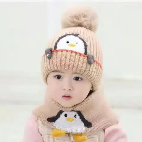 Child wearing a beige penguin hat with a fluffy pom-pom and matching scarf