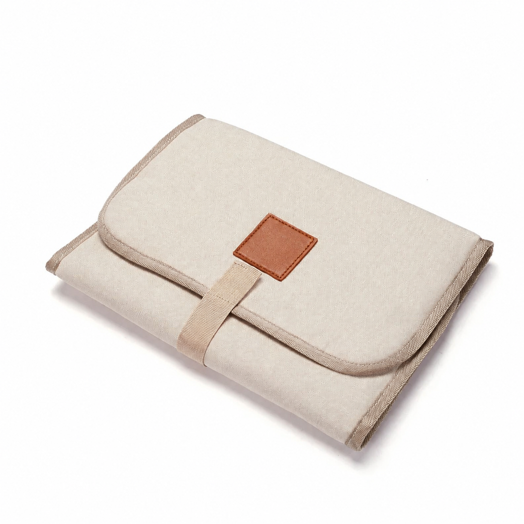 Beige portable changing mat shown folded with its front flap closed