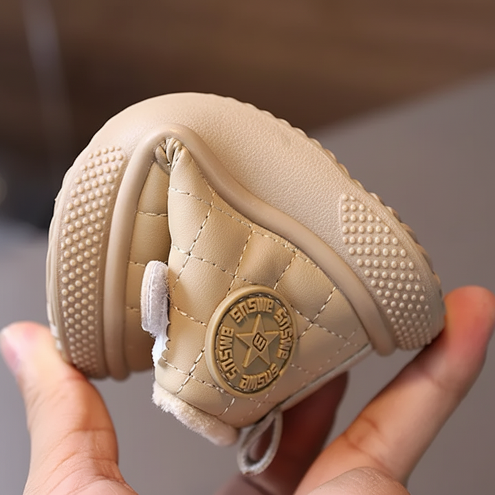 Beige quilted winter boot bent in one hand to show its sole and side