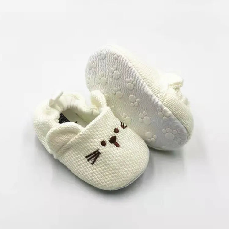Beige rabbit baby slippers showing an embroidered face and a textured paw-patterned sole