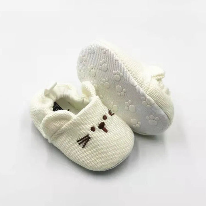 Beige rabbit baby slippers showing an embroidered face and a textured paw-patterned sole