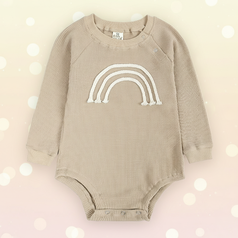 Front view of a beige long-sleeve baby bodysuit with a raised rainbow