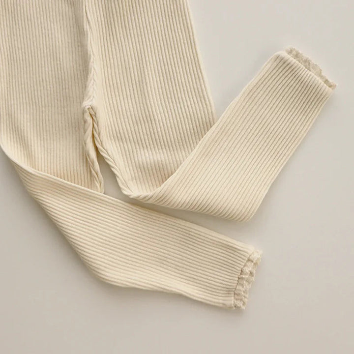 Beige ribbed leggings laid flat with crossed legs and lace-trimmed ankles.