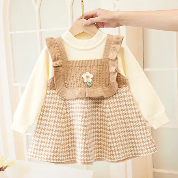 Beige dress held on a hanger with cream sleeves, ruffled trim, and a patterned skirt