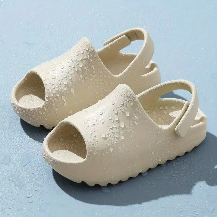 Beige open-toe sandals covered with water droplets on a blue surface.