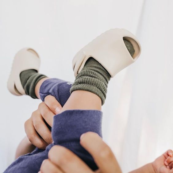 Child wearing beige open-toe sandals over ribbed socks.