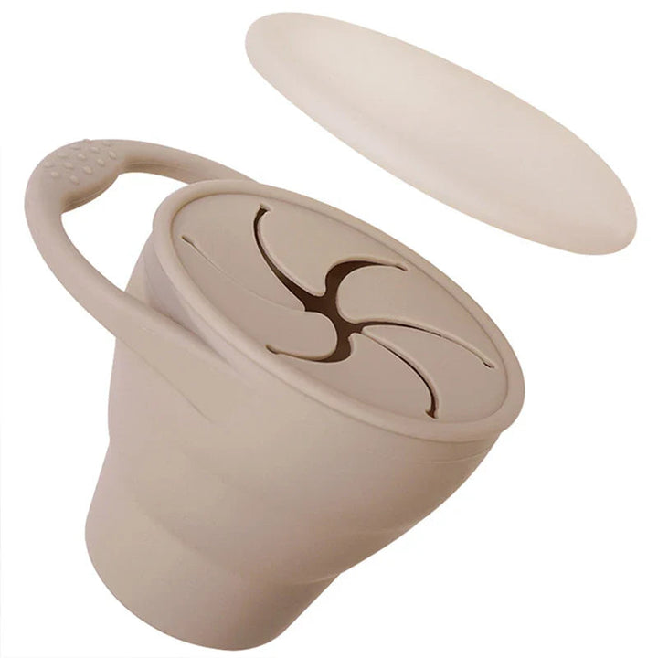 Beige silicone snack cup with a loop handle, flexible opening, and cover