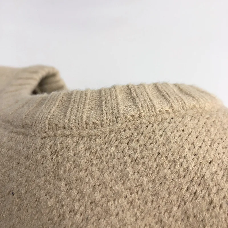 Close-up of beige knit fabric beneath the sweater&