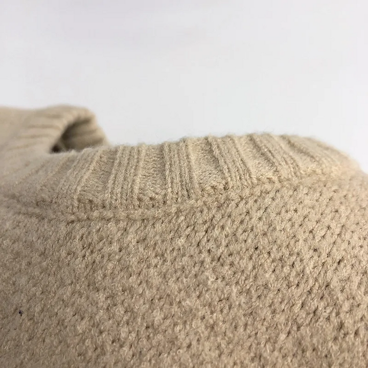 Close-up of beige knit fabric beneath the sweater&