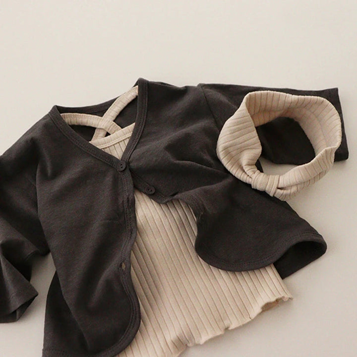 Beige ribbed tank styled with a black cardigan, cap, and fabric headband