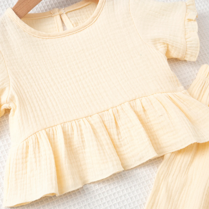 Front detail of the beige textured cotton top with its gathered ruffle hem
