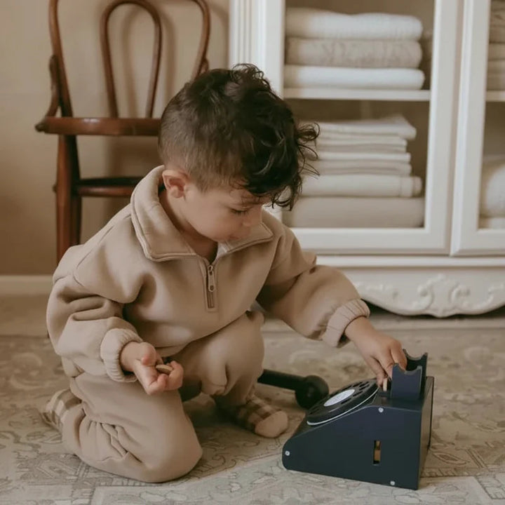 Child in a beige quarter-zip tracksuit playing indoors