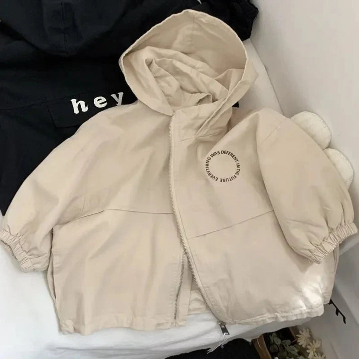 Front view of a beige hooded jacket with a zipper, elastic cuffs, and circular chest print