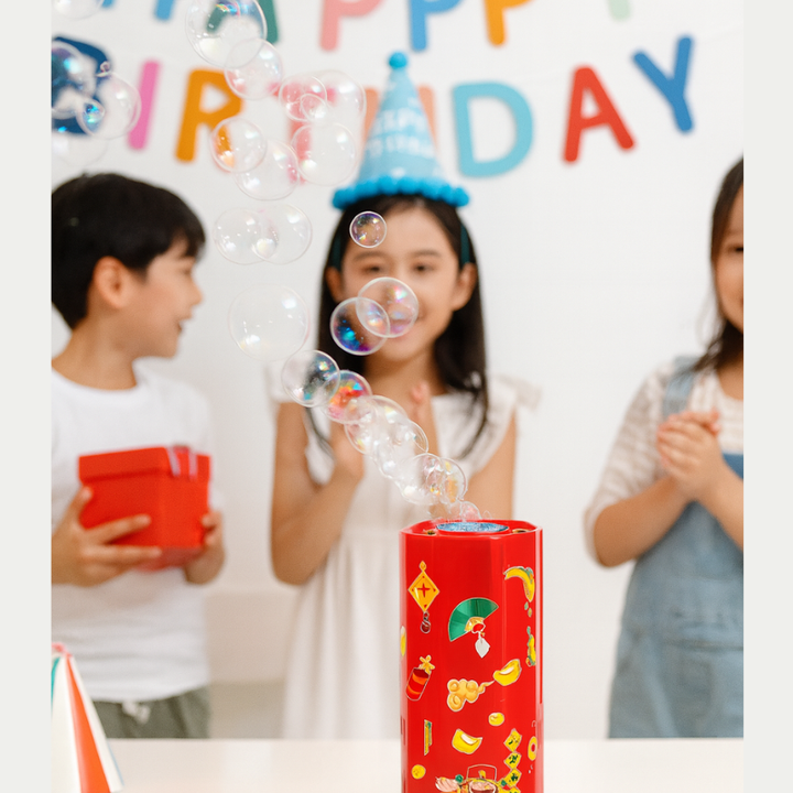 Children at a birthday party with bubbles floating above a red bubble machine
