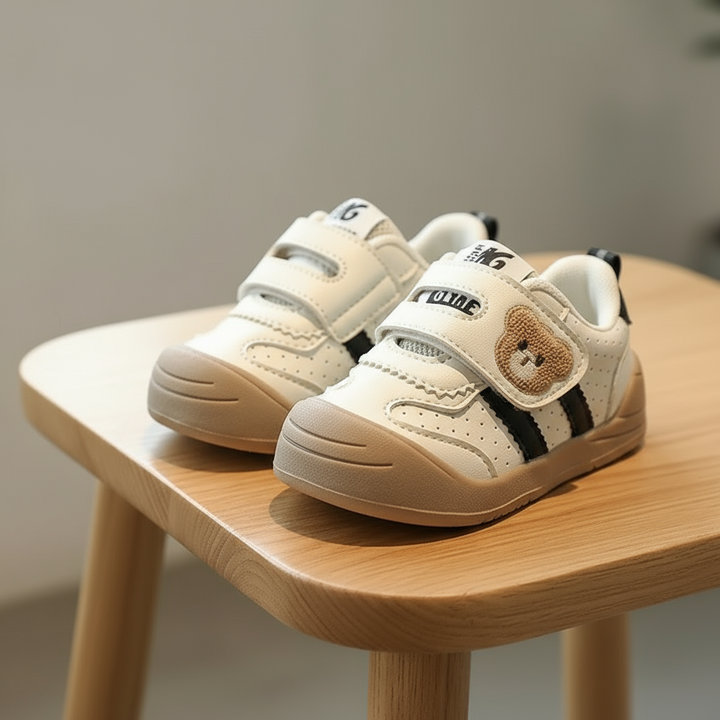 Black-accent bear sneakers with tan soles on a wooden surface