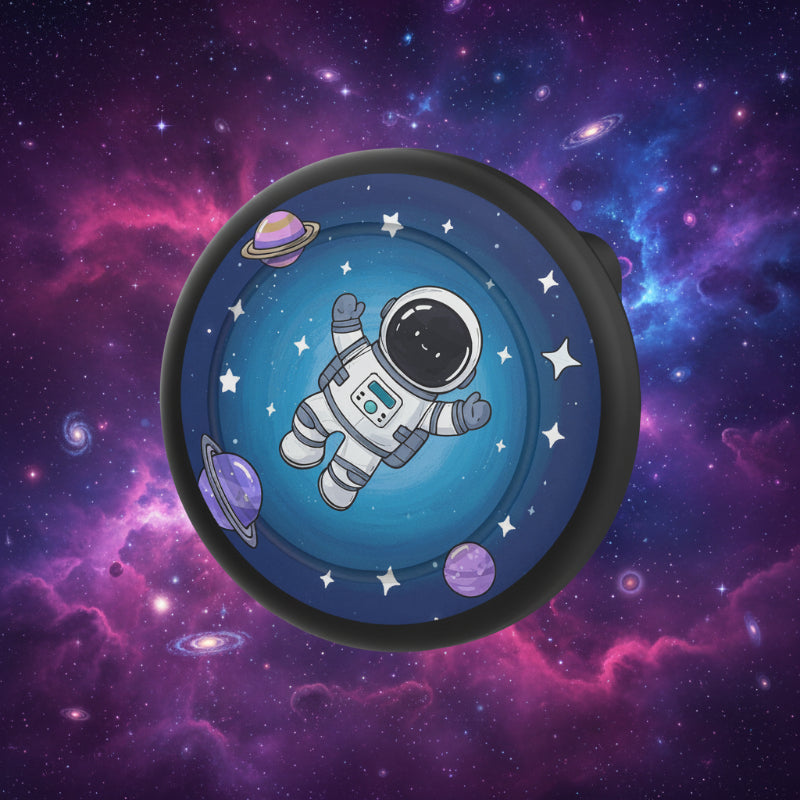 Black-rimmed AirTag brooch case with an astronaut and space-themed design
