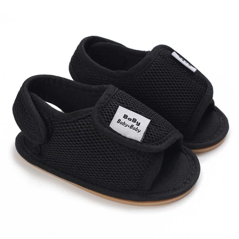 Black mesh baby sandals with adjustable straps and tan sole edges