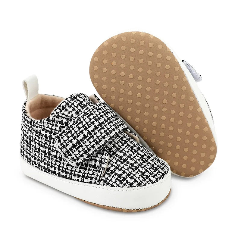 Black-and-white baby shoes showing the side profile and tan dotted outsole