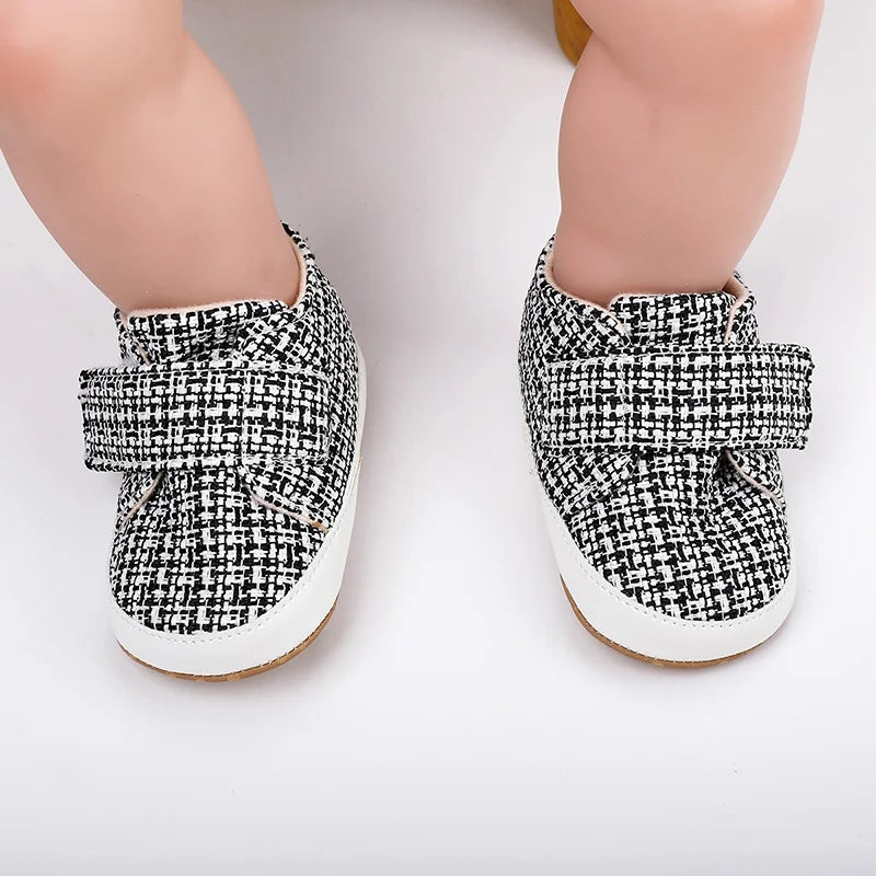 Front view of black-and-white baby shoes with wide straps fastened