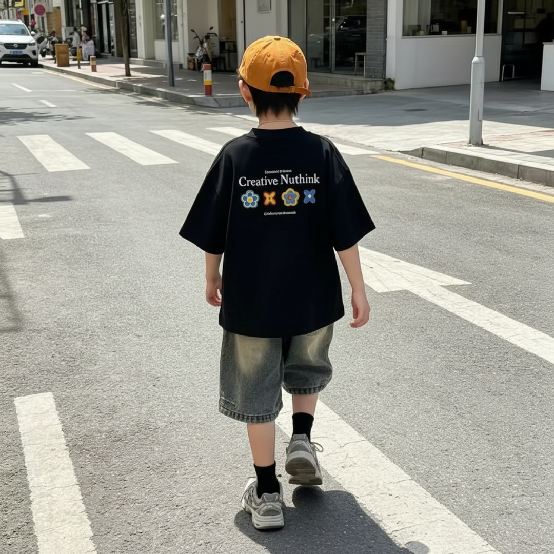 Boy walking across a street in a black graphic T-shirt and denim shorts