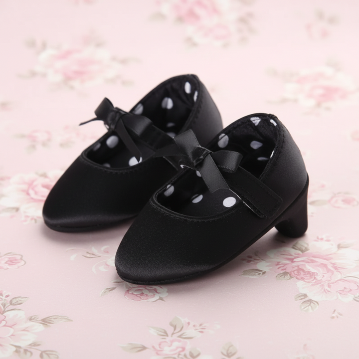 Black baby shoes with ribbon bows, straps, and polka-dot lining