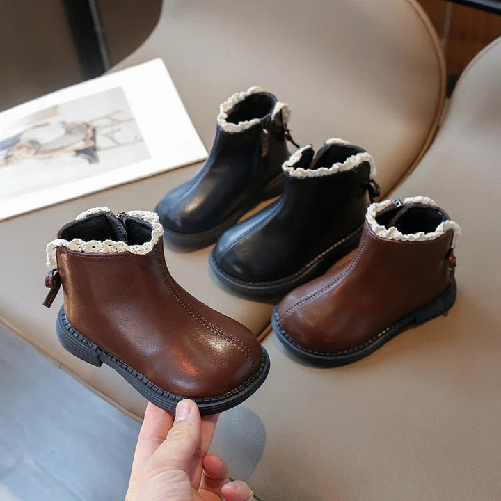 Brown and black ankle boots on a chair, with one brown boot held in front