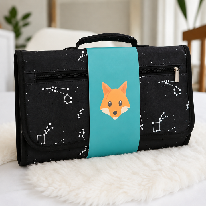 Black constellation-print changing mat with a teal band and fox illustration.