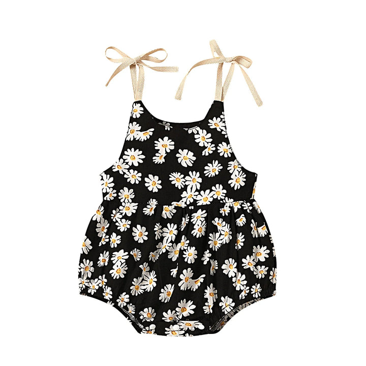 Black cotton baby romper with white flowers, a gathered waist, and bow-tie straps