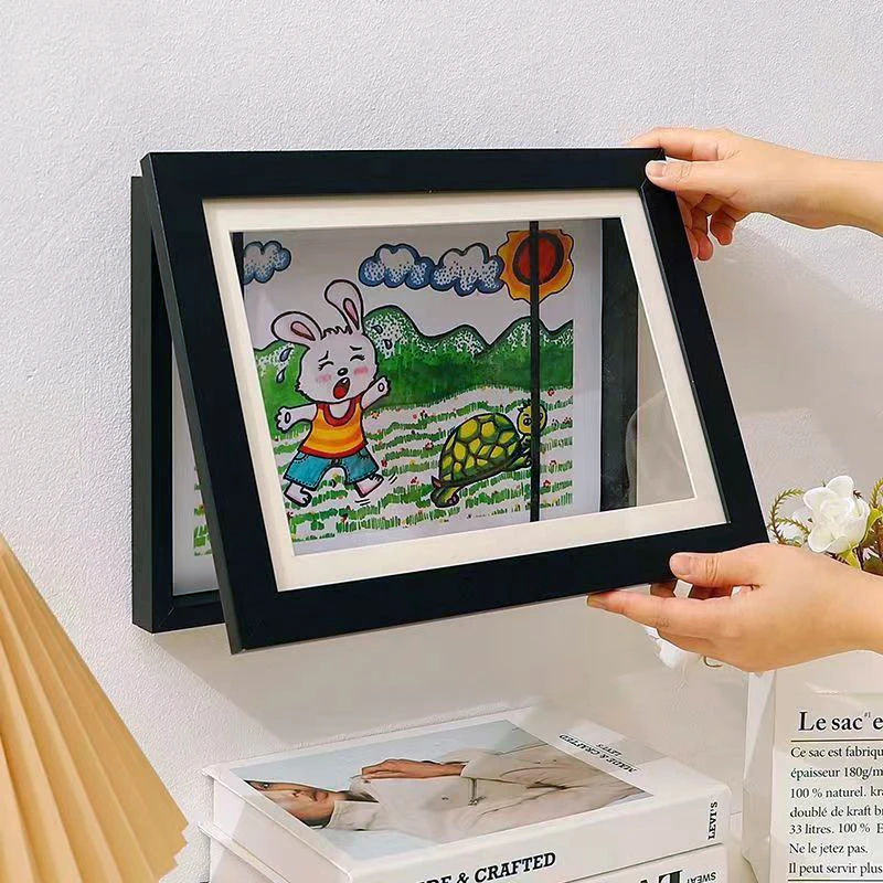 Hands opening a black art frame with a rabbit drawing