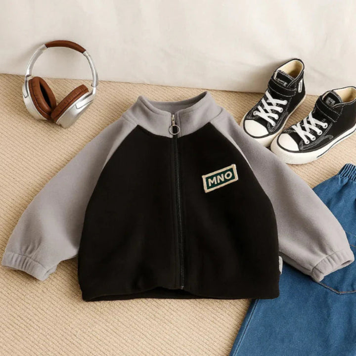 Black-and-gray fleece jacket laid flat beside jeans and sneakers