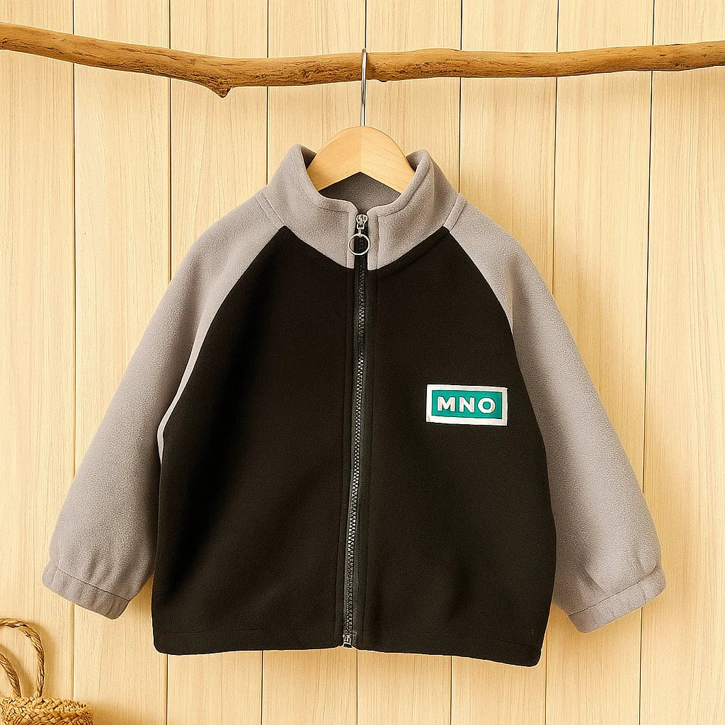 Black fleece jacket with gray sleeves hanging against a wood-paneled background