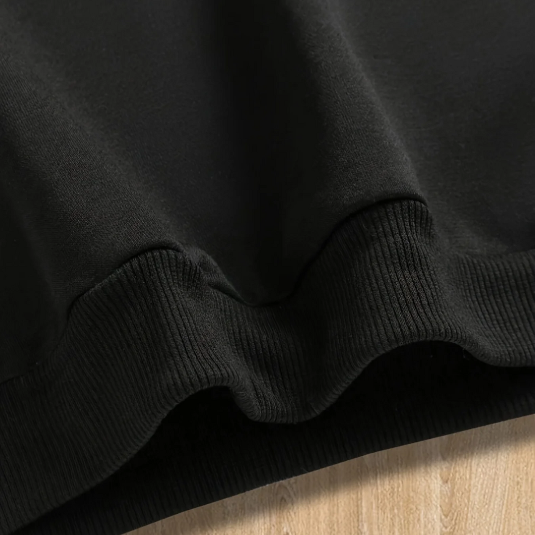 Close-up of the ribbed bottom hem on the black hoodie.