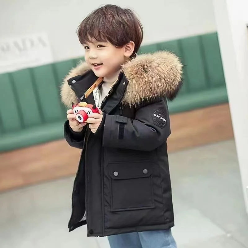 Child wearing a black winter coat with fluffy hood trim and front flap pockets