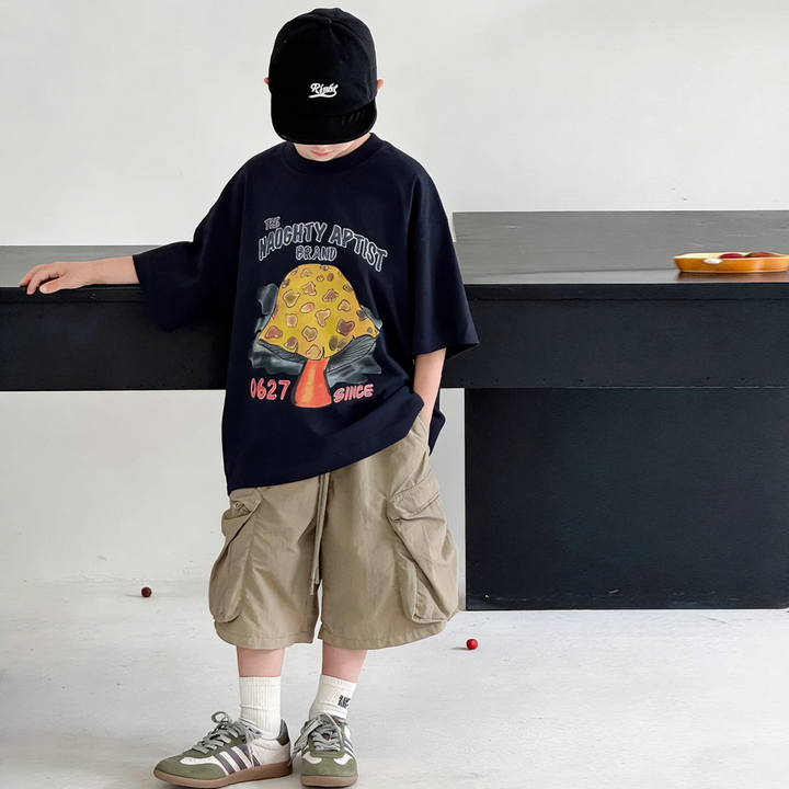 Child modeling the black mushroom graphic T-shirt with khaki cargo shorts