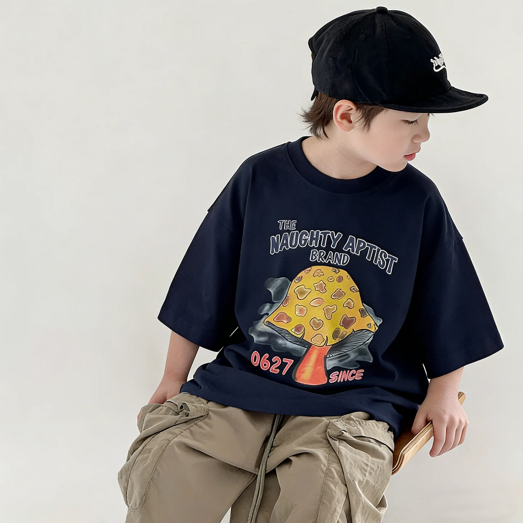 Child seated in a black oversized mushroom T-shirt and khaki shorts