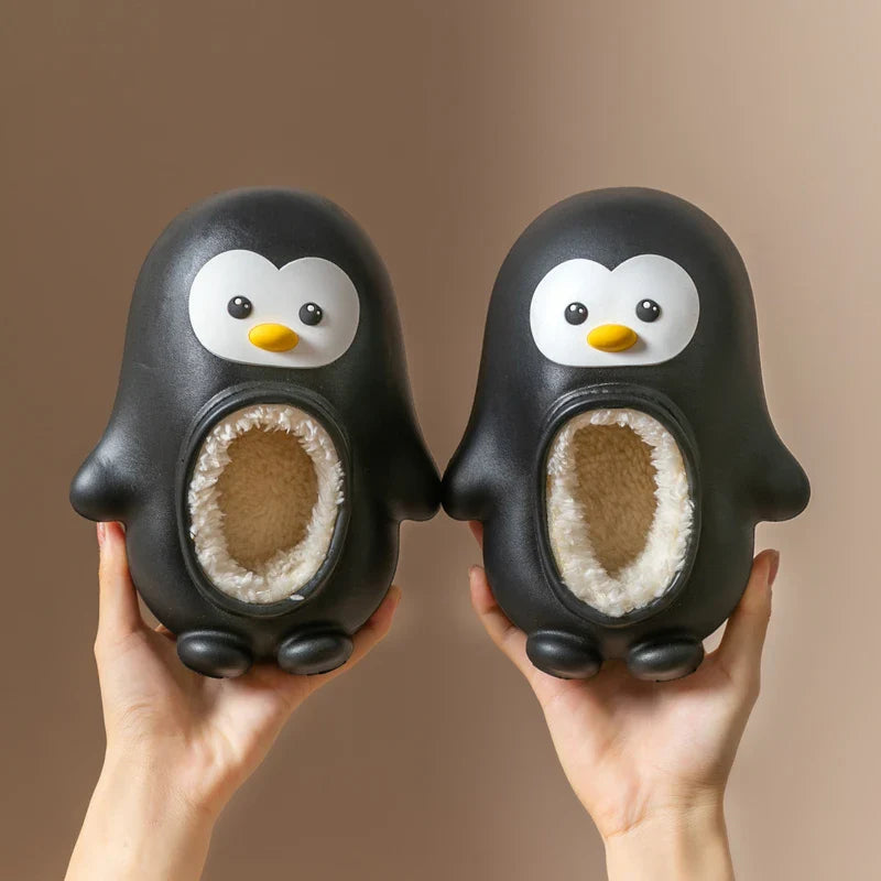 Pair of black penguin slippers with yellow beaks and cream-colored lining