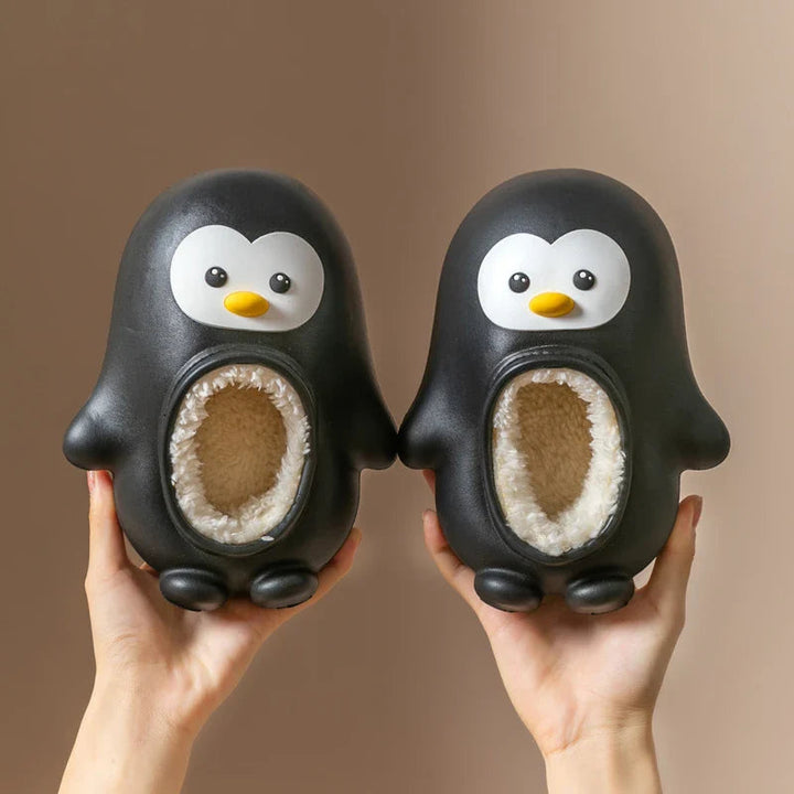 Pair of black penguin slippers with yellow beaks and cream-colored lining