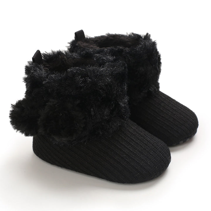 Black baby boots with ribbed uppers and fluffy pom-pom accents