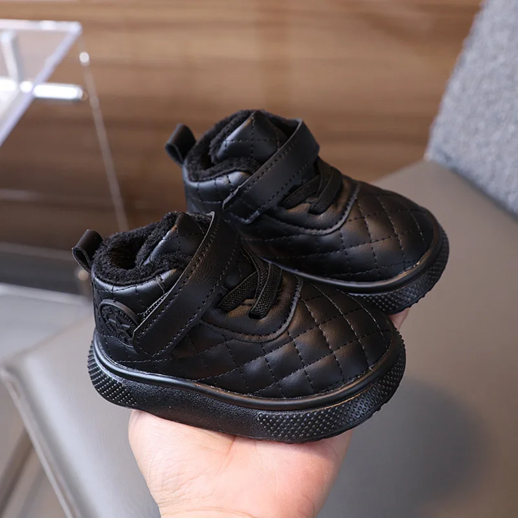 Pair of black quilted winter boots with matching soles held in one hand