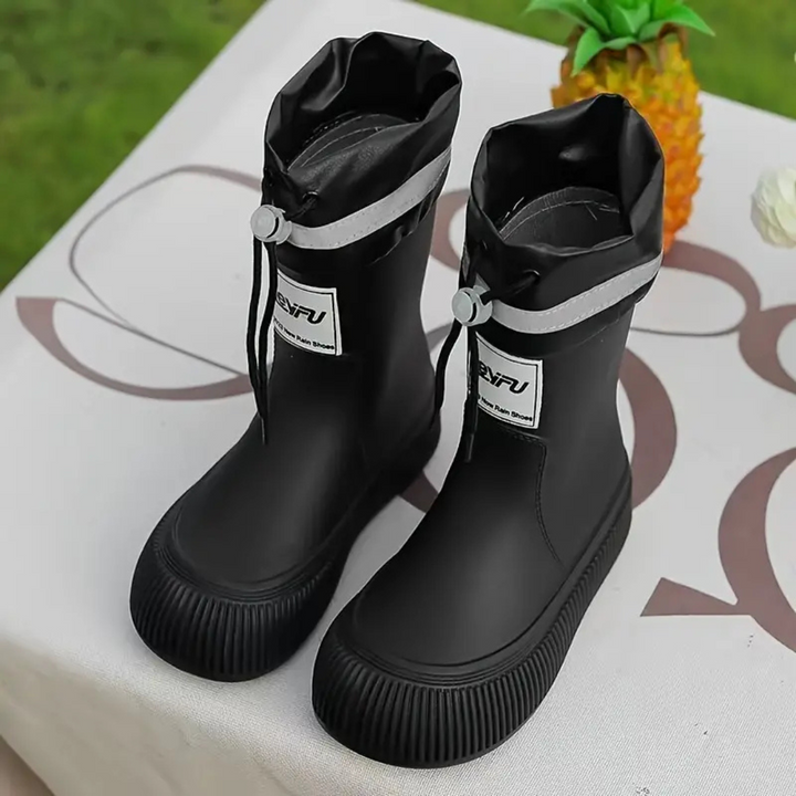 Pair of black rain boots with gray cuff bands on a patterned outdoor table
