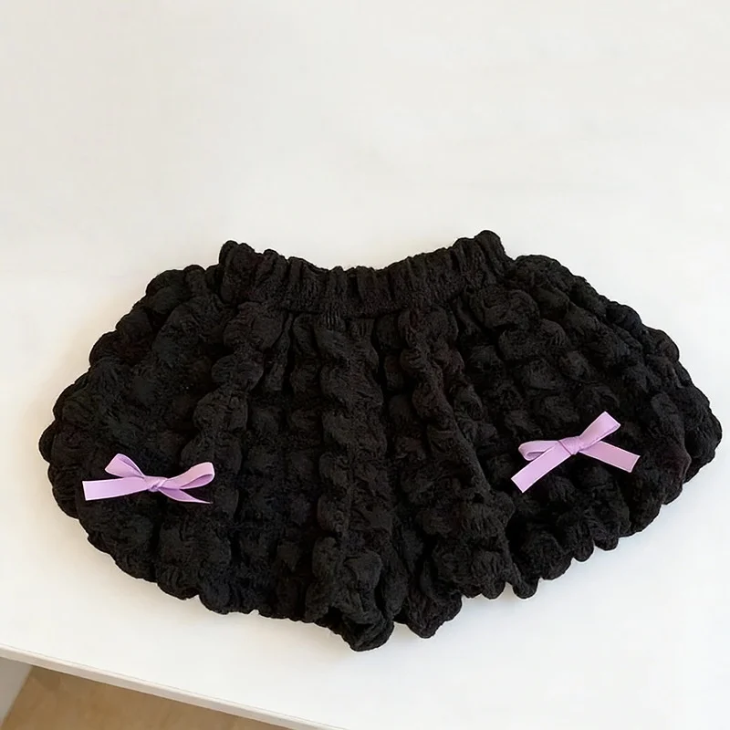 Black ruffle shorts with a gathered elastic waist and two lavender bows