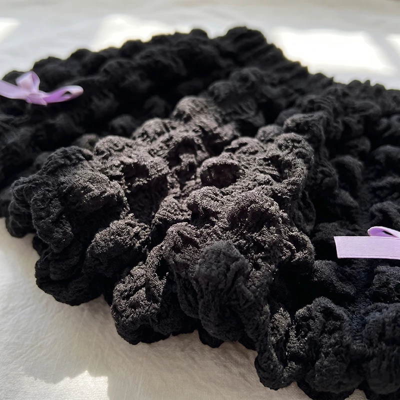 Close-up of the ruffled fabric texture and lavender bows on black shorts