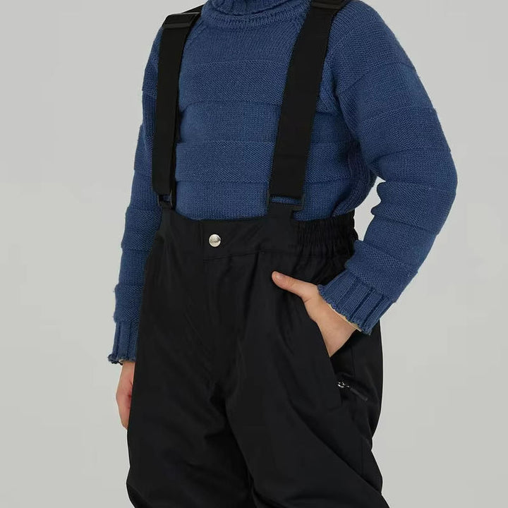 Close-up of black ski pants with shoulder straps, a gathered waist and side pockets.