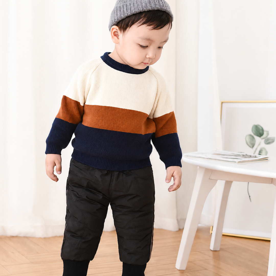 Child wearing black padded winter pants with a striped sweater indoors