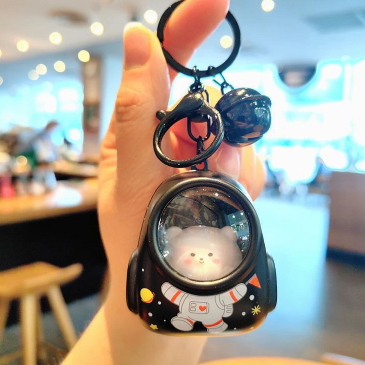 Black astronaut capsule charm with space illustrations, a matching key ring, and bell