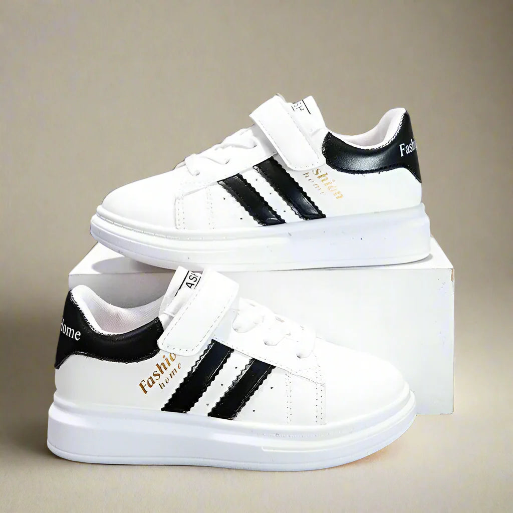 White sneakers with black side stripes and heel accents displayed on a box.