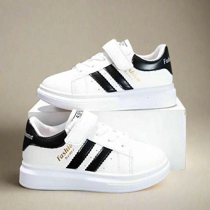 White sneakers with black side stripes and heel accents displayed on a box.